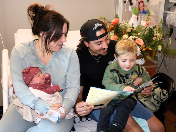 Text Box: Photo: Baby girl Rhona O’Hara, one day old, listens to her older brother Walter, and parents Lauren and Walter Sr., read the book gifted to her by the Read to Me program: “The Snail and the Whale” by Julia Scheffler. 